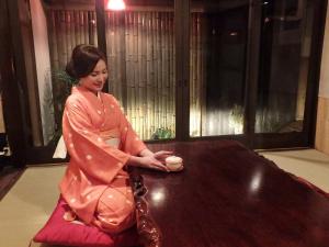Eine Frau, die an einem Tisch mit einer Tasse Kaffee sitzt. in der Unterkunft YUMEJI Vintage Villa in Kyoto