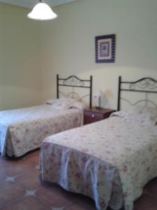 a bedroom with two beds and a table and a lamp at El Balcón de la Mancha in Tembleque