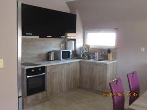 a kitchen with wooden cabinets and a microwave and a window at Bogorodi Terrace Apartment in Burgas