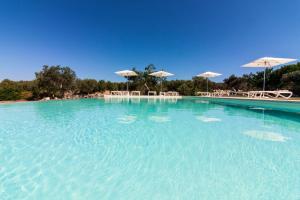 ein großer Pool mit blauem Wasser, Tischen und Sonnenschirmen in der Unterkunft Montiro' Hotel in Santa Maria di Leuca