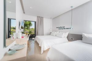 a white bedroom with two beds and a table at Venus Resort in Tsilivi