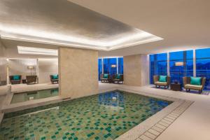 a swimming pool in a hotel lobby with a view of the city at Ascott Raffles City Shenzhen in Shenzhen