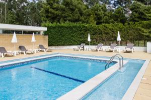 una piscina con tumbonas y una piscina en Hotel ibis Porto Sul Europarque, en Santa Maria da Feira