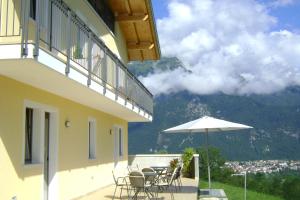 einen Balkon mit einem Tisch, Stühlen und einem Sonnenschirm in der Unterkunft Affittacamere Rubino Guest House in Ponte nellʼAlpi