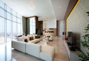 a living room with white furniture and large windows at Fraser Suites Diplomatic Area Bahrain in Manama