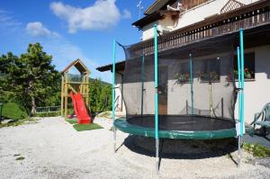 a playground with a trampoline in front of a house at Albergo Passo Brocon in Castello Tesino