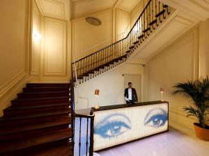 a man standing next to a staircase with eyes painted on the wall at Axel Hotel Madrid - Adults Only in Madrid