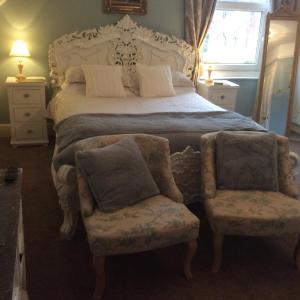 a bedroom with a large bed and two chairs at Anchorage House in Whitby
