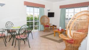 a room with a table and chairs and windows at Apartamentos Quinta da Praia in Alvor