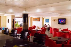 a restaurant with red chairs and tables and a flat screen tv at BWC Hotel in Lagos