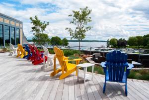 uma fila de cadeiras e mesas coloridas num deque em Tall Ships Landing Coastal Resort em Brockville