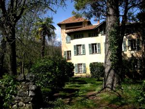 Una casa vieja con un árbol delante. en Domaine du Paraïs B&B, en Sospel