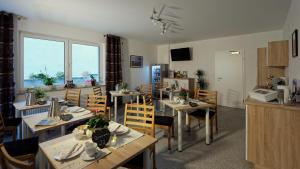a dining room with tables and chairs and windows at Gästehaus Am Hochsimmer in Ettringen