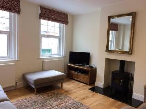 sala de estar con TV y espejo en Brockenhurst Apartments, en Brockenhurst