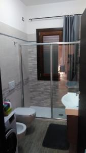 e bagno con doccia, servizi igienici e lavandino. di Rooms Loru a Sestu