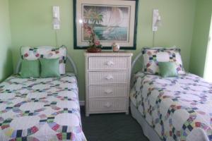 a bedroom with two twin beds and a dresser at Sunrise Resort by Liberte' in St. Pete Beach