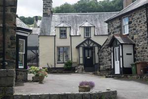 una antigua casa de piedra con un patio frente a ella en Plas Gwyn B&B and Holiday Cottage en Dolgellau