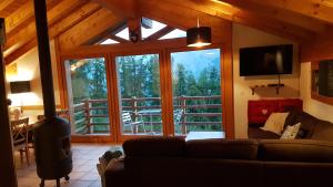 uma sala de estar com um sofá e uma grande janela em Chalet Chaperon Rouge em Nendaz