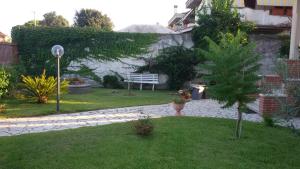 kobieta przechodząca przez ogród z ławką w obiekcie B&B La villetta rossa w Anzio
