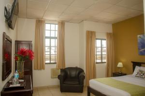 a bedroom with a bed and a chair and windows at Hotel Residencial Cervantes in David