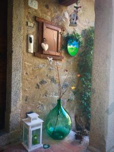 a green vase with a plant in it next to a wall at B&B El Piastrol in Bagolino