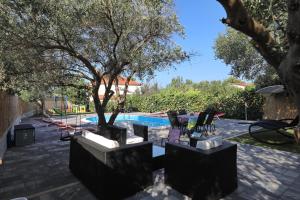 a patio with a pool and trees and chairs at Apartment with private pool in Sukošan