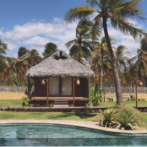 a small hut next to a swimming pool with palm trees at Pousada Vayú in Icaraí