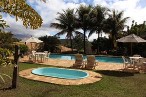 a swimming pool with a table and chairs and a swimming pool at Pousada Lapa Grande in Serra do Cipo
