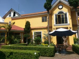 a yellow house with an umbrella in front of it at Hotel Farah in Nuevo San Juan Parangaricutiro