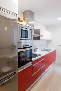 uma cozinha com armários vermelhos e um micro-ondas em Apartamento El Arce em Foz