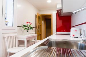 a kitchen with a sink and a red wall at Apartamento El Arce in Foz +8 photos