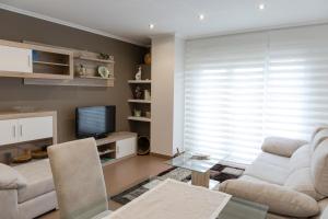 uma sala de estar com um sofá e uma televisão em Apartamento El Arce em Foz