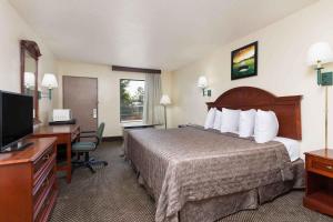 Habitación de hotel con cama, escritorio y TV. en Heritage Inn Augusta en Augusta