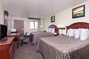 a hotel room with two beds and a desk and a television at Heritage Inn Augusta in Augusta