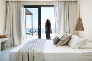 a woman standing in a bedroom looking out the window at Casa di mare in Svoronata