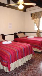 a bedroom with two beds with a red blanket at Hotel Calle Ancha in Antigua Guatemala