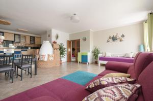 salon z fioletową kanapą i kuchnią w obiekcie Casa Lavanda w Alsóörs