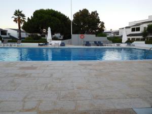 una gran piscina con sillas y sombrillas en Villa Benedito, en Charneca