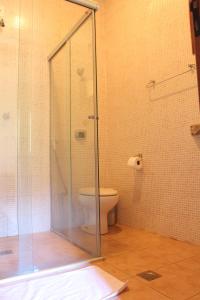 a bathroom with a toilet and a glass shower at Pousada Lapa Grande in Serra do Cipo