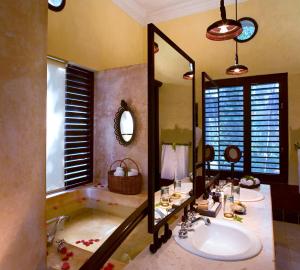 a bathroom with a tub and a sink and a mirror at Hacienda Uayamon in Uayamón