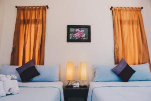 a bedroom with two beds and orange curtains at Baan Klong Resort in Damnoen Saduak