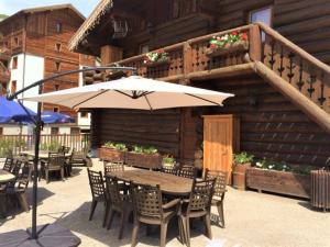 patio con tavolo, sedie e ombrellone di Chalet Le Ranch a Les Deux Alpes