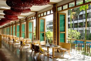 - une salle à manger avec des tables, des chaises et des fenêtres dans l'établissement Welcome World Beach Resort & Spa, à Pattaya (sud)
