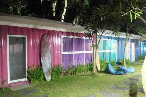 uma casa cor-de-rosa com uma prancha de surf ao lado. em Kubu Container em Uluwatu