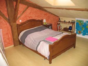 ein Schlafzimmer mit einem Holzbett im Dachgeschoss in der Unterkunft La Croix De Camargue in Oradour-sur-Glane
