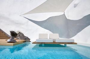 Ein Zimmer mit Pool, zwei Betten und einem Sonnenschirm in der Unterkunft Villa Etheras in Firostefani