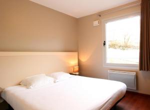 a bedroom with a large white bed with a window at Aux Balcons du Sancy in Picherande