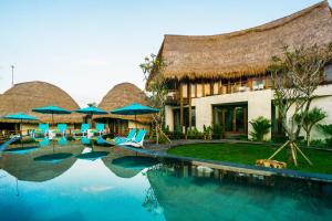 a resort with a swimming pool with chairs and umbrellas at C-View Villas in Nusa Lembongan