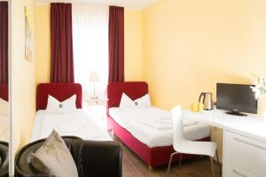 ein Hotelzimmer mit 2 Betten und einem Schreibtisch in der Unterkunft Barcelona Bed & Breakfast in Düsseldorf