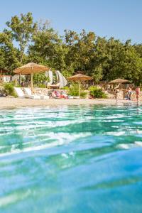 a swimming pool with umbrellas and a beach with people at Krk Mobile Homes in Klimno